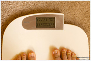 Two feet standing on a bathroom scale with a digital display reading 'You're not serious??'