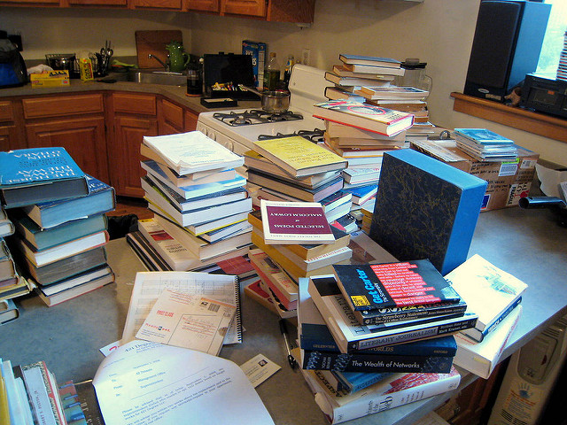 A cluttered kitchen counter covered in hard cover and paperback books in various states of repair. Photo credit: walkering on Flickr.