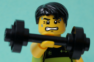 A sweating Lego figure attempting to lift a toy barbell with one hand. Photo credit: pasukaru76 on Flickr.